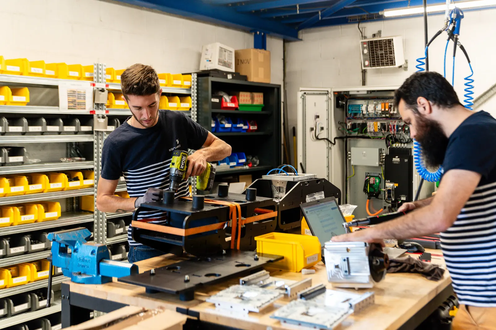 Dos miembros del equipo Stirweld trabajan con herramientas en su taller.