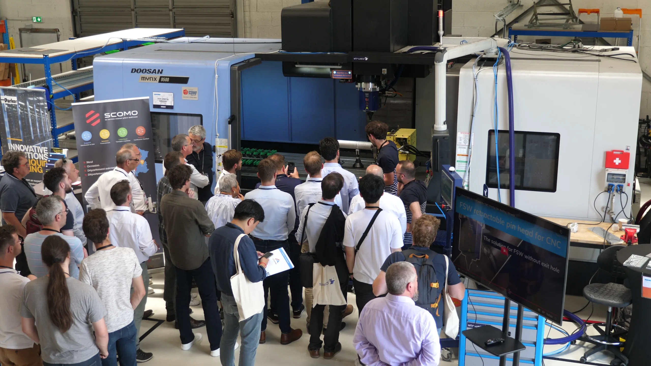 Varias personas observan el funcionamiento de una máquina herramienta CNC Doosan en el taller de Stirweld mientras realiza una soldadura FSW.